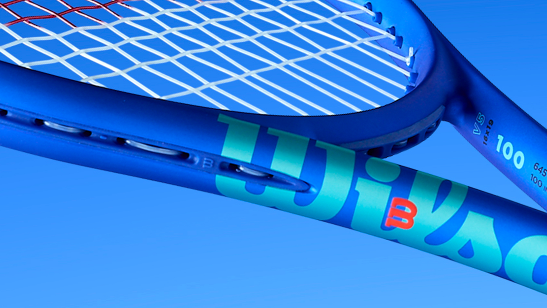  Close-up of a blue tennis racket with Wilson branding against a blue background